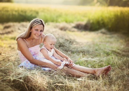 Happy young mother having fun with her little daughter in summer natureの写真素材