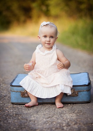 Cute little girl is having fun in the old suitcaseの写真素材