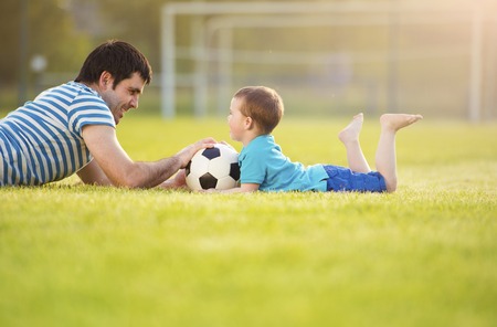Young father with his little son having fun on football pitchの写真素材