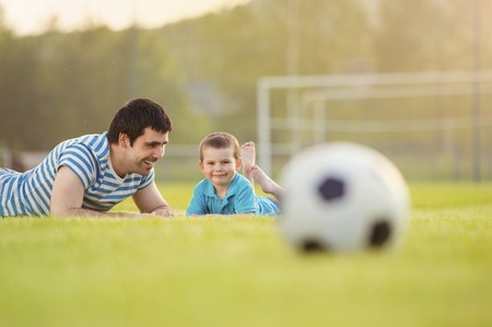 Young father with his little son having fun on football pitchの写真素材