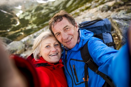 Senior tourist couple hiking and taking selfie at the beautiful mountains