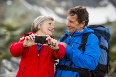 Senior tourist couple hiking and taking selfie at the beautiful mountainsの写真素材