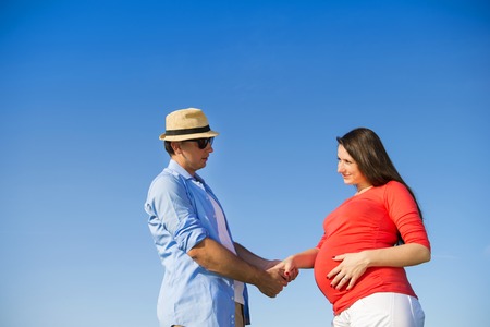 Portrait of young pregnant couple with blue skyの写真素材