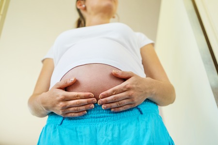 Close-up of unrecognizable pregnant woman with hands over tummy