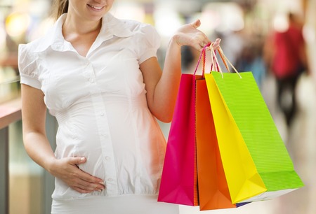 Young pregnant woman with shopping bags in shopping mallの写真素材