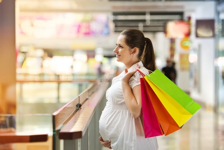 Young pregnant woman with shopping bags in shopping mallの写真素材