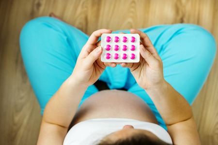 Portrait of unrecognizable pregnant holding pills in her handsの写真素材