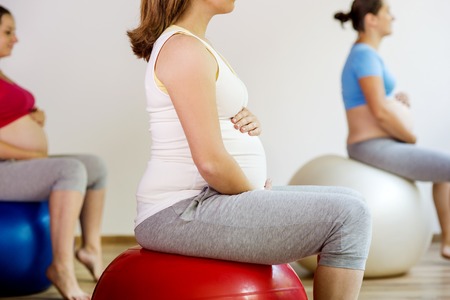 Young pregnant women doing exercise using a fitness ballの写真素材