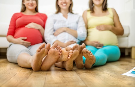 Three pregnant women sitting in front of sofaの写真素材