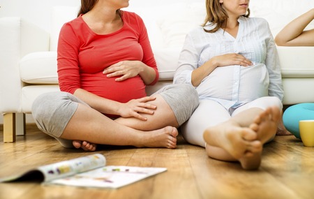 Three pregnant women sitting in front of sofaの写真素材