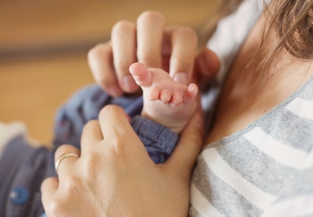 Mother playing with baby feet at homeの写真素材