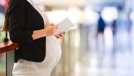 Detail of pregnant belly and digital tabletの写真素材
