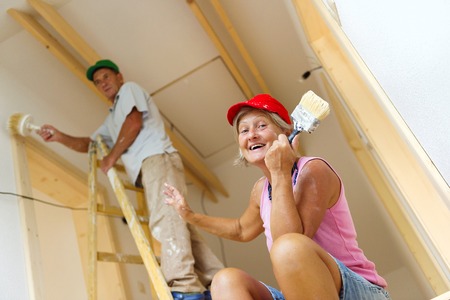 Active senior couple painting wall with brush in new house  They are having fun の写真素材