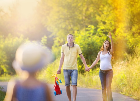 Happy pregnant family having fun during the walk in summer natureの写真素材
