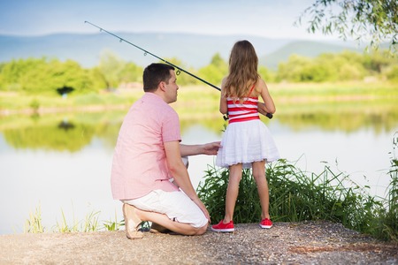 Happy young father fishing on the lake with his little daughterの写真素材