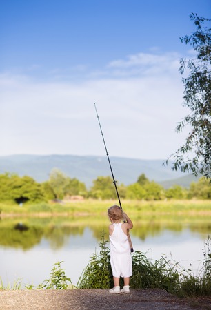 Cute little girl fishing on the lake withの写真素材