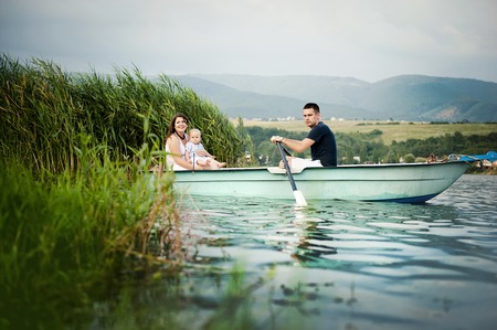 Mother and father with baby boy on boat on lakeの写真素材