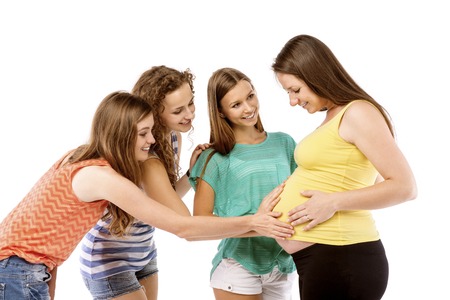 Female friends touching tummy of a pregnant woman, isolated on white backgroundの写真素材