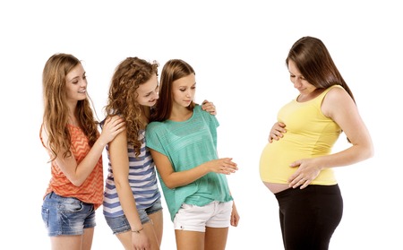 Female friends looking at tummy of a pregnant woman, isolated on white backgroundの写真素材