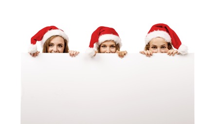 Group of young women in santa hats holding copy space, isolated on white backgroundの写真素材