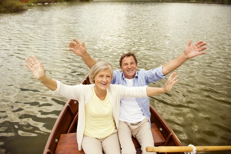 Senior couple waving to the camera on boat on mountain tarnの写真素材