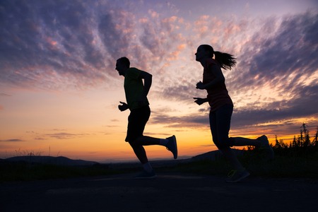 Silhouette of young couple running in sunset