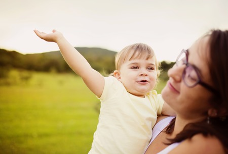 Portrait of happy little daughter and her mother in the park