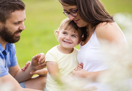 Happy pregnant family having fun in summer natureの写真素材