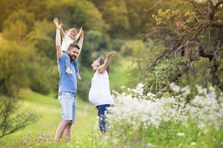 Happy pregnant family having fun in summer natureの写真素材