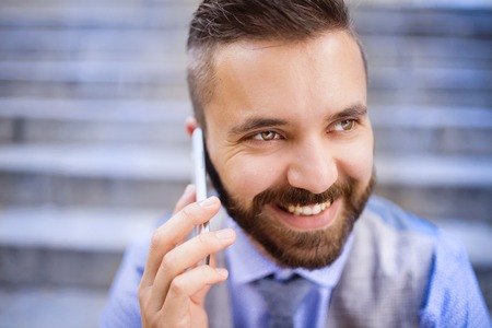 Detail of handsome hipster modern businessman using smart phone in the cityの写真素材