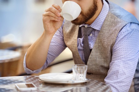 Detail of modern hipster businessman drinking espresso coffee in the city cafe during lunch timeの写真素材