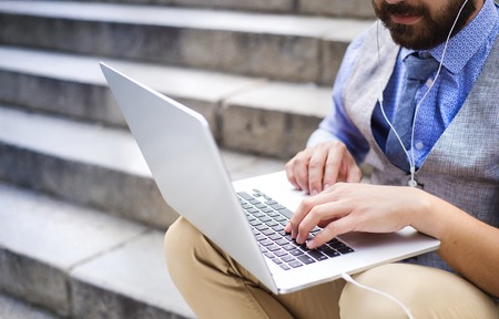Detail of modern hipster businessman sitting on the stairs and using laptopの写真素材