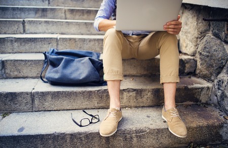 Detail of modern hipster man´s feet sitting on the stairs and using laptopの写真素材
