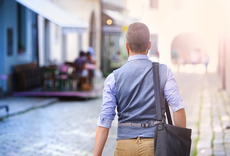 Handsome hipster modern businessman with briefcase walking in townの写真素材