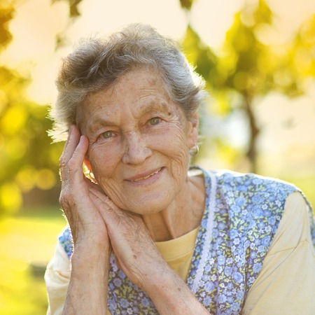 Portrait of senior woman in apron in the sunny garden