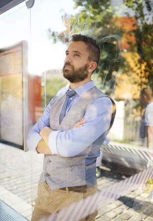 Handsome hipster modern man waiting for bus on bus stopの写真素材