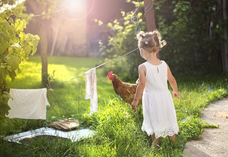 Happy little girl having fun in garden near the old farmhouseの写真素材