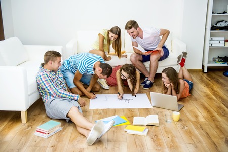 Group of young students studying together and preparing for exams in home interiorの写真素材