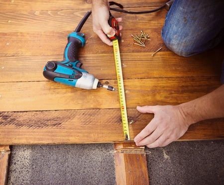 Close up of male hands measuring wood flooring with tape measureの写真素材