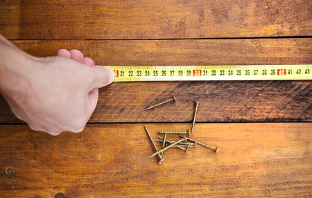 Close up of male hand measuring wood flooring with tape measureの写真素材