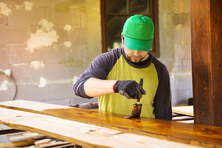 Handyman varnishing pine wooden planks in patio outside the new houseの写真素材