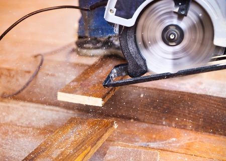 Electric grinder machine left on dusty wooden flooring with wood shavingsの写真素材