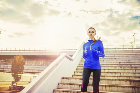 Female runner running down the stairs in city center