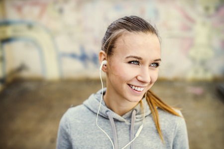 Young female runner is having break and listening to music in the streetの写真素材