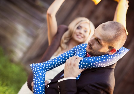 Happy bride and groom on their wedding day having fun with love cushions outside in the gardenの写真素材