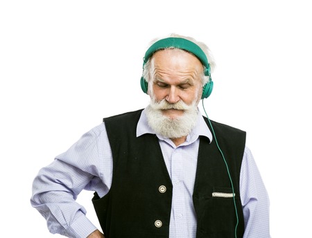 Old active bearded man with headphones listening to music isolated on white backgroundの写真素材