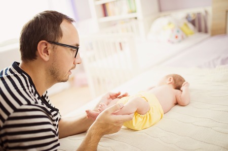Happy young father enjoying special moments with his newborn baby daughter at homeの写真素材