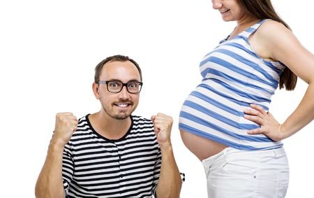 Portrait of young pregnant couple posing in studio, isolated on white backgroundの写真素材