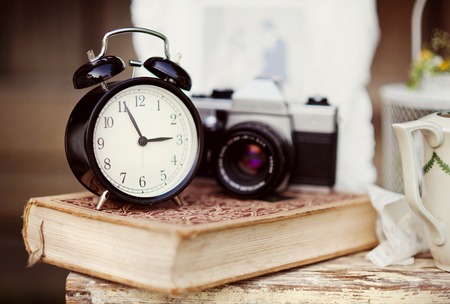 Group of objects on vintage wooden table. old alarm clock, retro camera, bookの写真素材