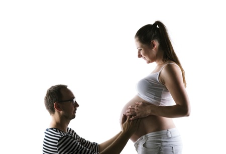 Silhouette of young pregnant couple posing in studio, isolated on white backgroundの写真素材